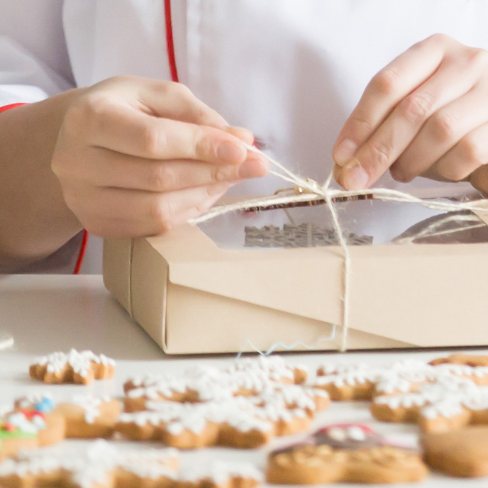 Pasticcere che annoda nastro su scatola per biscotti